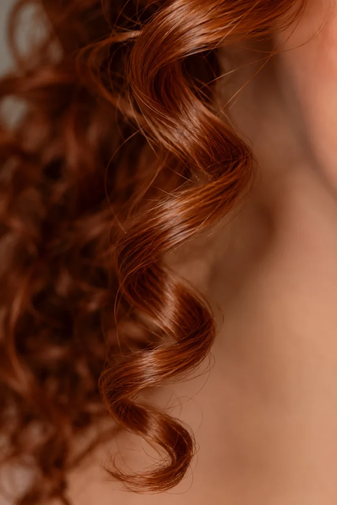 Makro-Aufnahme einer einzelnen roten Spirallocke zur Veranschaulichung natürlicher Haarstruktur bei Lockenschnitten